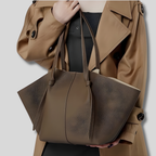 Sac cabas Novélya en cuir marron porté à l’épaule avec trench beige – vue lifestyle élégante