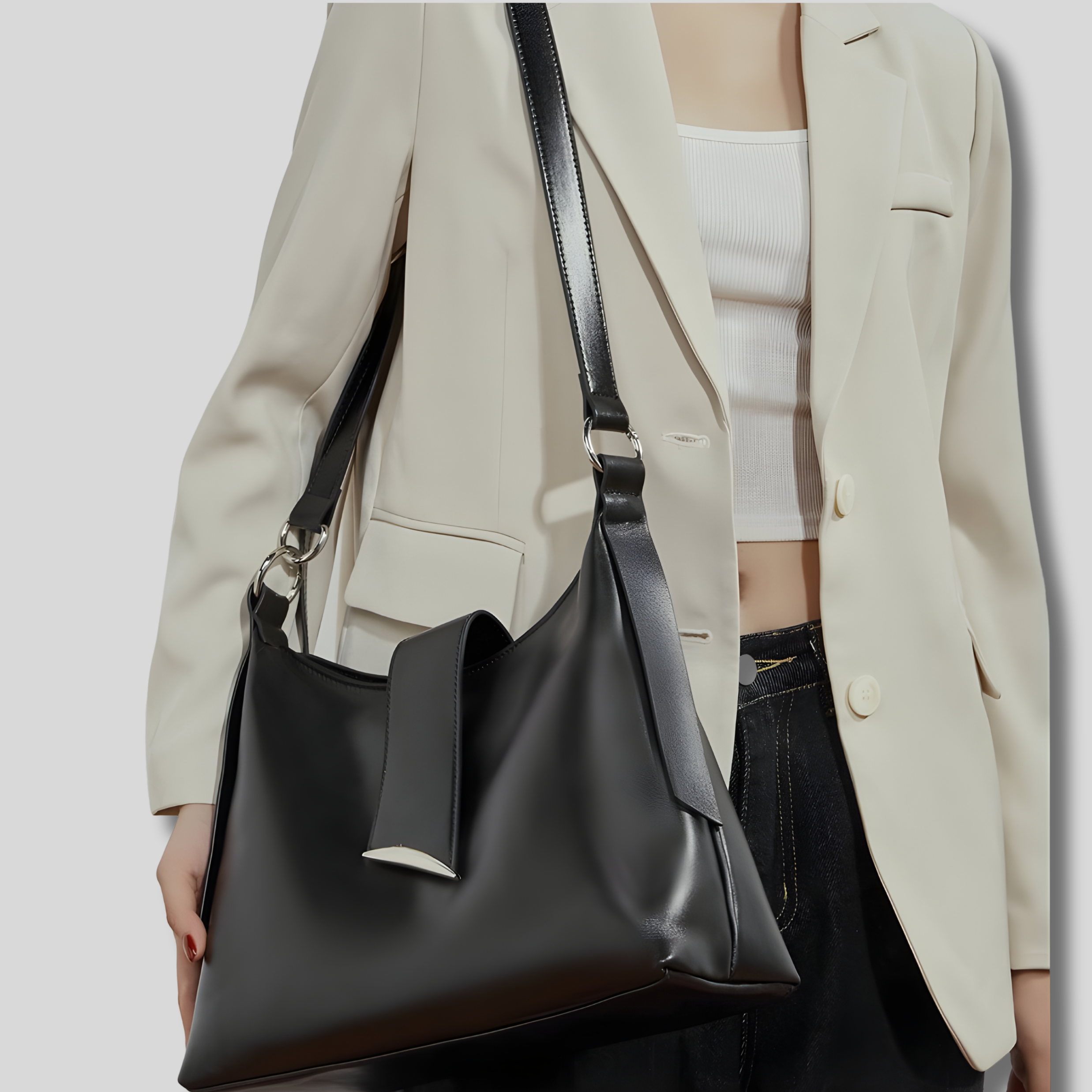 Sac bandoulière en cuir noir porté croisé sur modèle, silhouette minimaliste élégante, détail boucle métallique argentée.