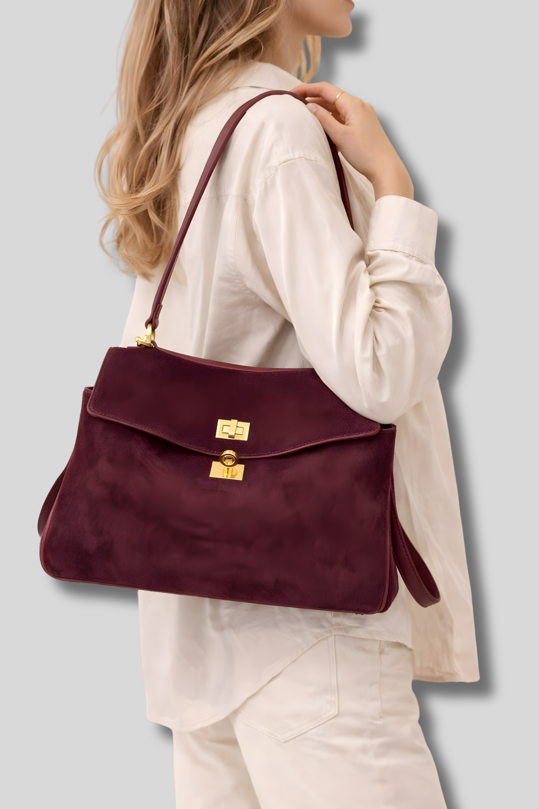 Femme portant un sac bandoulière en suède bordeaux élégant sur l’épaule