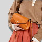 Sac bandoulière marron Arvane porté à la main, élégant et compact pour un usage quotidien