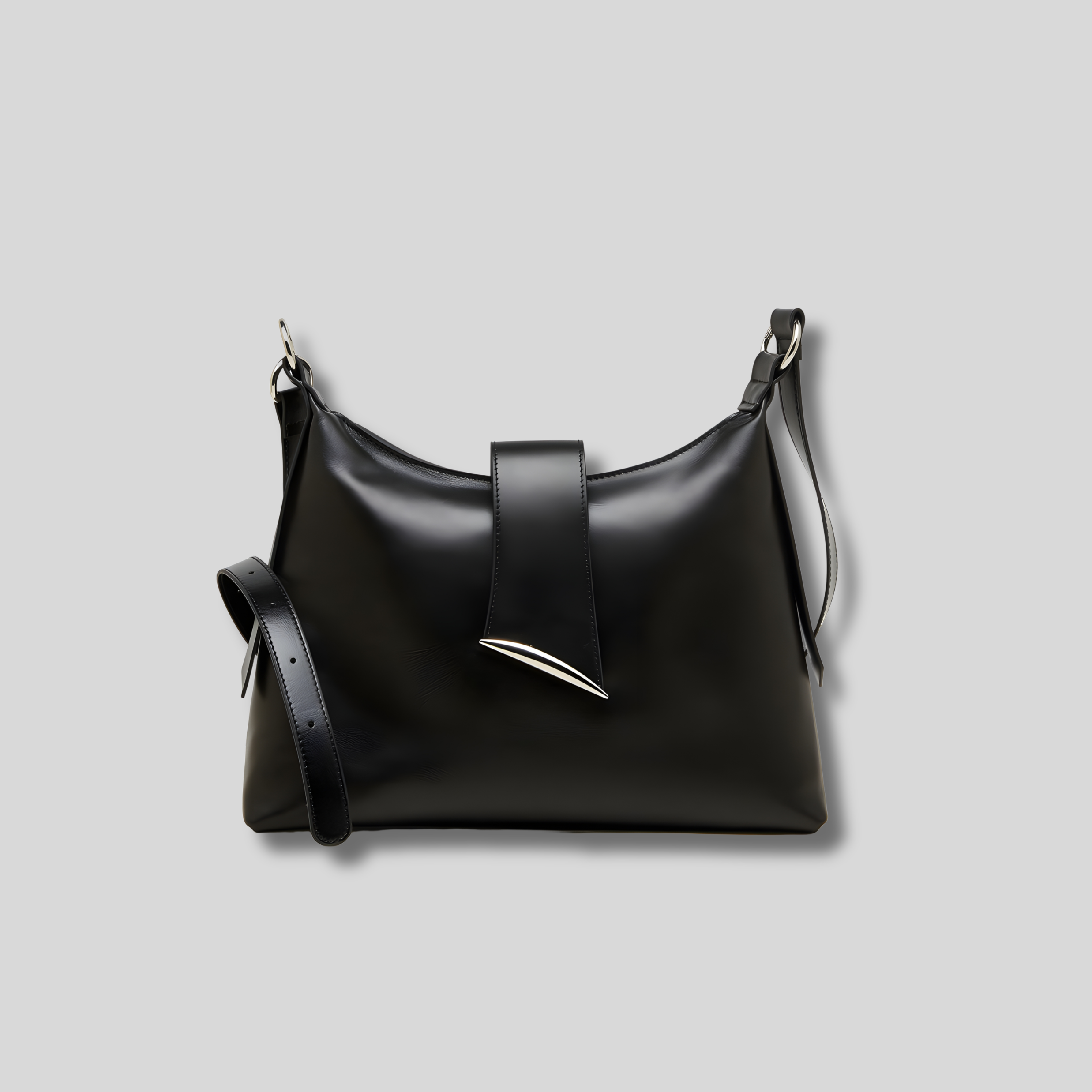 Sac bandoulière en cuir noir, forme souple minimaliste, bandoulière réglable et détail métallique signature.