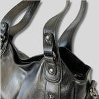 Détail du sac en similicuir noir, finition des anses et coutures avec attache métallique résistante