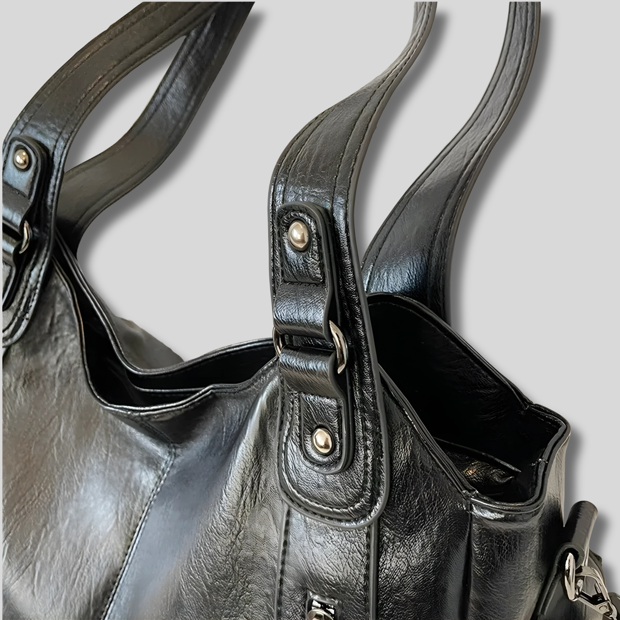 Détail du sac en similicuir noir, finition des anses et coutures avec attache métallique résistante