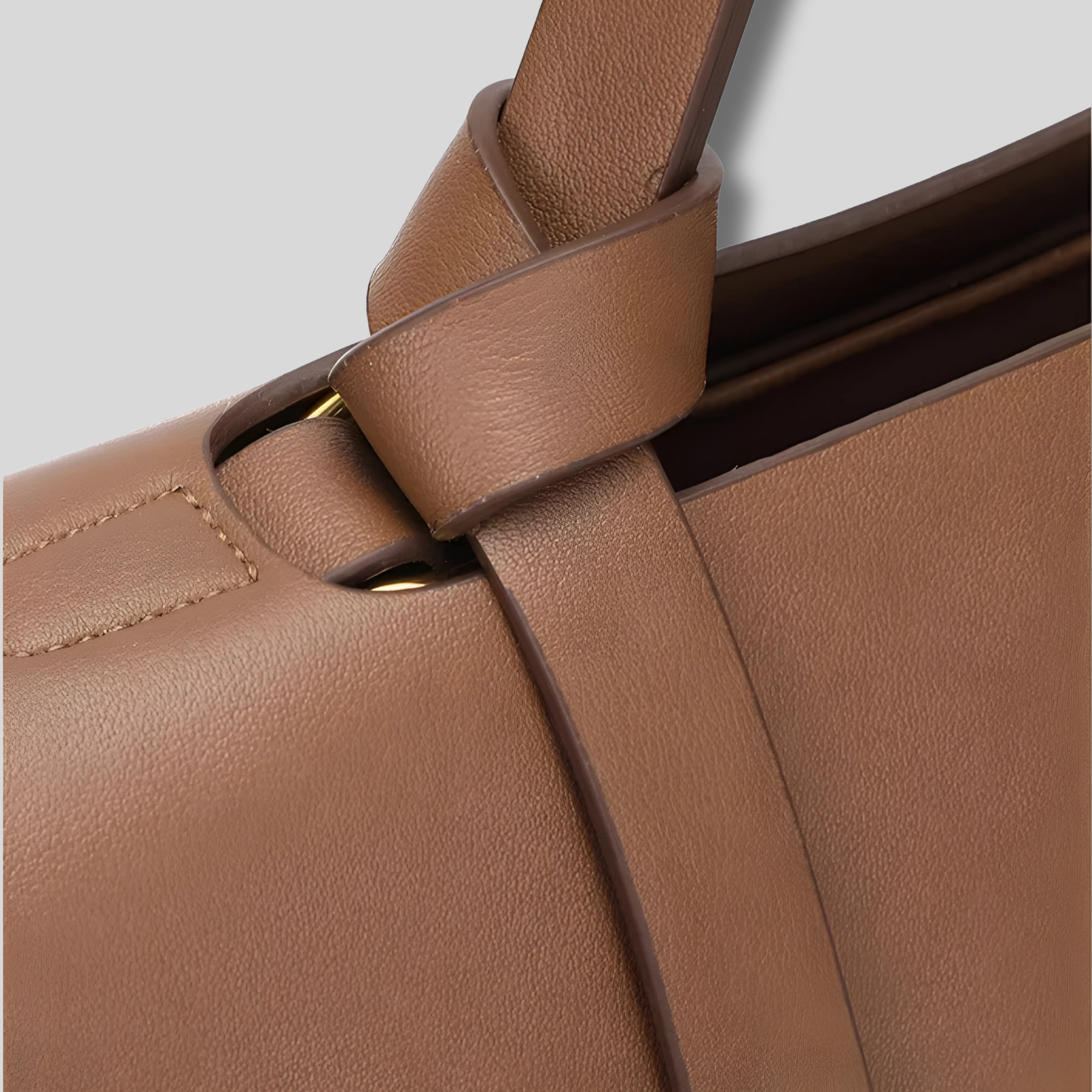 Détail de la poignée en cuir nouée avec finition texturée et anneau doré.