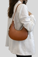 Sac demi-lune marron porté à l’épaule par une femme, style élégant et minimaliste, parfait pour un usage quotidien.